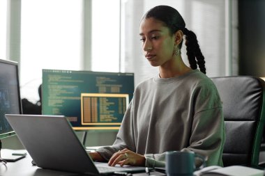 Orta Doğu 'lu kadın programcının bilgisayar başında bilgisayar başında bilgisayarlarla çalışırken orta boy görüntüsü.