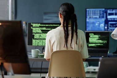 Orta Doğulu kadın programcının arka görünüşü saç stili kodlaması ile IT şirketinin ofisindeki birden fazla bilgisayarda.