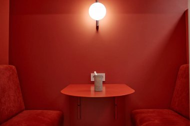 Masanın arka plan görüntüsü kırmızı kafe standının canlı gölgesinde, duvarda minimalist tasarım ve aydınlatma lambası, kopyalama alanı