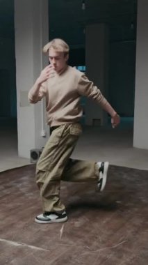 Dikey bıçak darbesi, beyaz erkek, hip hop giysileri içinde rock 'n' roll yaparken boş salonda boombox müzik eşliğinde break dans yaparken.