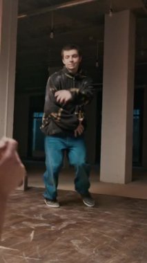 Sokak kıyafetleri içindeki beyaz Z-Boy 'un enerji ve ifade dolu nefes kesici akrobatik break dans hareketleri yaparken arkadaşlarının onu izlediği ve desteklediği dikey çekimi.