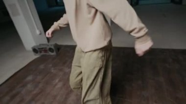 En iyi rock hareketlerini sergileyen, kapalı dans salonunda tek başına müzik eşliğinde doğaçlama yapan sokak elbiseli beyaz çocuk.