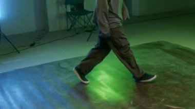 Sokak kıyafetleri içinde sakallı genç beyaz adamın el kamerası görüntüsü. Yaratıcı kırma hareketleri sergiliyor. Dans salonunda pratik yapıyor.