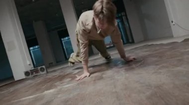 Sokak kıyafetleri içindeki beyaz erkek zoomer 'ın sahne çekimi içeride break dans yaparken yaratıcılığını gösteren rock hareketlerini gösteriyor.