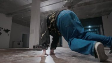 Yaratıcı Kafkas jenerasyon Z B-Boy 'un şehir kıyafetleri içinde rock hareketlerini icra ederken, kapalı alanda dans ederken.