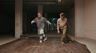 Şehir kıyafetleri içinde dans eden, aynı anda aynı kırılma hareketlerini yapan iki yetenekli beyaz B-boy 'un tam karesi.