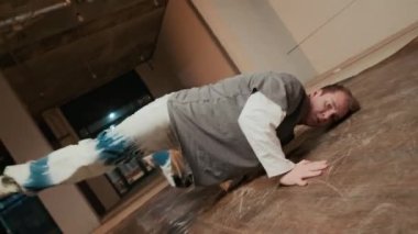 El kamerasıyla, sokak stili giysileri içinde beyaz erkek zoomer 'ın dans salonunda, titreşimli ışık altında amuda kalkarken, amuda kalkarken çekilen sahne.