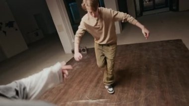 Arkadan çekilen, kentsel giyim giymiş, rock yapan, arkadaşının önünde dans eden, onu destekleyen, müzik eşliğinde dans eden beyaz çocuk.