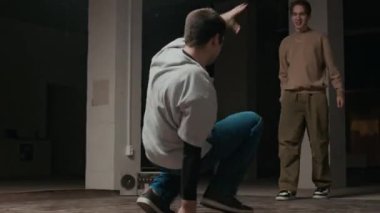 Kafkas jenerasyonu Z B-boy 'un, akranlarının önünde dans figürleri yaparken, kapalı mekanda müzik eşliğinde pratik yaparken elde çekilmiş bir fotoğrafı.