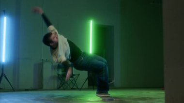 Yavaş yavaş, yeşil ve mavi lambaların altında vücudunu döndüren ve nefes kesici akrobatik hareketler yapan beyaz dansçı.