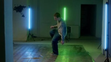 Şehir kıyafetleri içinde yeşil ve mavi renkli ışıkla dans salonunda çalışırken moladan keyif alan yetenekli Kafkas jenerasyonundan Z-boy.