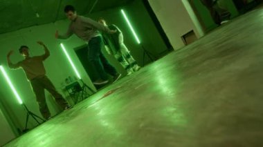 Şehir kıyafetleri içindeki yetenekli Z-B-Boy 'un sahne çekimi akranlarının önünde breakdance yapıyor, hip hop kültürünü serinletiyor ve yeşil ışık altında dans pistinde eğleniyor.