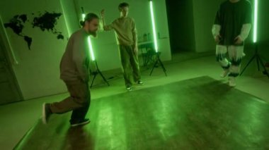 Sokak elbiseli, beyaz sakallı genç bir adam dans savaşında yeşil ışıklı odadaki genç meslektaşlarının önünde harika yetenekler sergiledi.