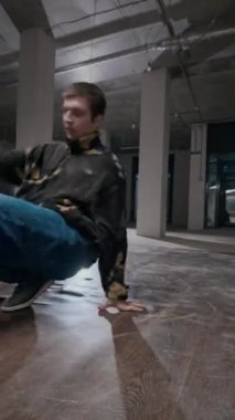 Kentsel giyimde dans figürlerini icra eden, dans pistinde müzik eşliğinde dans eden yetenekli beyaz çocuk dikey çekimi.