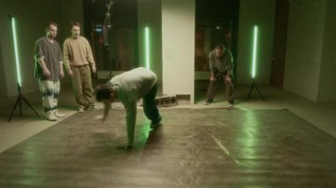 Genç beyaz erkek zoomer 'ın dans pistinde destekçilerinin önünde dans edişini izlemek.