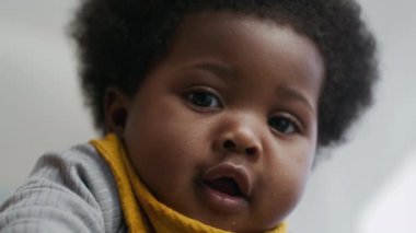 Meraklı bir ifadeyle bebeğe yakın çekim, büyük heyecanlı gözler ve hafif yarık dudaklar.