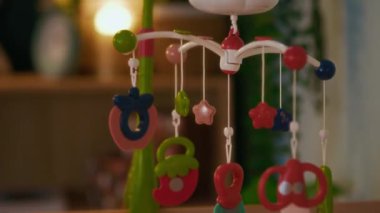 Hiçbir insan, renkli daireler, yıldızlar ve soyut şekilleri bebek odasındaki ahşap karyolanın üzerinde asılı olan canlı bebek arabasının yakın çekimini yapmasın.