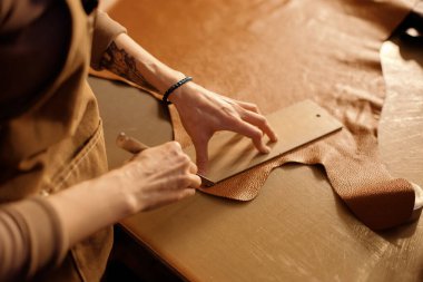 Bir atölye masasında ustaca deri kesen zanaatkarlık ve detaylara dikkat göstergesi. Süreç hassas araçlar ve sağlam eller gerektirir.