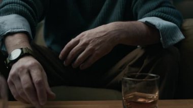 Olgun bir adamın alyansını çıkarıp eski karının fotoğrafına koyduğu, viski şişesiyle masaya oturduğu ve alkolle acıyı dindirmeye çalıştığı kesikli raflar.