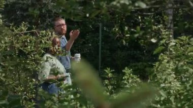 Genç beyaz adamın kahve fincanı ile parlak bir yaz gününde genç ağaçları tartışan genç Afrikalı Amerikalı bir kadınla yürüyüş yaparken çekilmiş bir fotoğrafı.