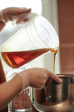 Pastanenin mutfağında zanaatkar ekmeği pişirirken, ölçüm kabındaki malzemeleri karıştırırken tatlı altın şurubu döken kadın pasta şefinin ellerine dikey yakın çekim.