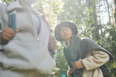 Güneşli yeşil ormanda sırt çantasıyla seyahat eden turistlere alçak görüş açısı, boşluğu kopyala