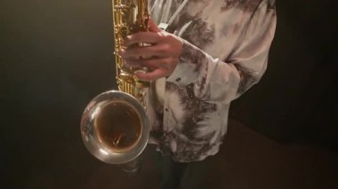 Orta yaşlı yetenekli beyaz bir adamın dramatik dumanlı karanlık sahnede ilham ve müzik tutkusu dolu bir saksafonda solo çalmasını çek.