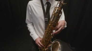 Orta yaşlı, yetenekli, beyaz erkek müzisyenlerin klasik kıyafetler giyip saksafonda bebop çalarken, arka planda ustaca çalarken çekilen çekimler.