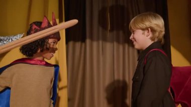 Tiyatroda prova sırasında kostümlü, kral ve ejderha rolünde iki farklı çocuk oyuncu.
