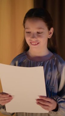 Sahnede durup okul tiyatrosunda senaryo okuyan neşeli beyaz kız.