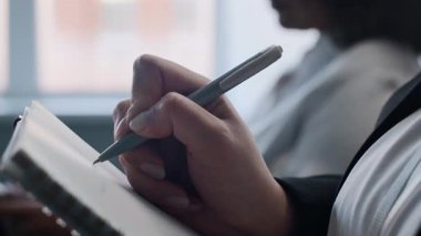 Konferans sırasında not defterine notlar yazan tanınmayan iş kadınının eli kapalı.