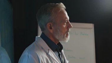 Orta yaşlı Kafkas doktoru konferans sırasında yeni tıbbi teknolojiler hakkında konuşuyor.