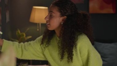 Çift ırklı Z jenerasyonlu kızın planlarını çizelgeye yazıp yurt odasının duvarına astığının yan görüntüsü.