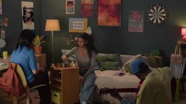 Etnik açıdan farklı üç arkadaş grubu dağınık yurt odasında satranç ve gitar oynayarak vakit geçiriyorlar.