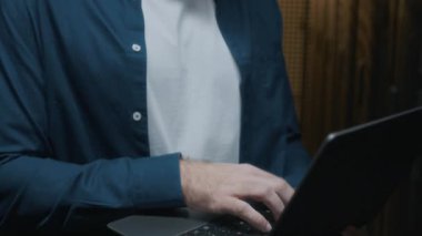 Veri merkezindeki raf sunucu dolabının bakımını laptopla kontrol ederek günlük kıyafet ve gözlük konusunda uzman beyaz tenli bir erkeğin yakın çekim görüntüsünü al.