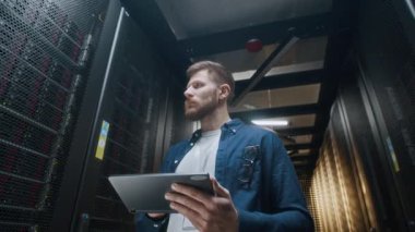 Veri merkezindeki sunucu odasında dijital tablet kullanarak günlük giysi teftiş dolabında çalışan Kafkas erkek bilişim teknisyeninin düşük açılı çığlığını büyüt