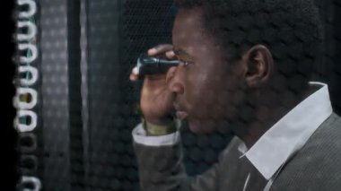 Formalite içinde genç siyahi erkek bilişim mühendisinin sunucu odasındaki ana bilgisayara el feneriyle baktığı görüntüleri yakından takip et.