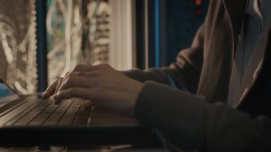 Bilgi merkezindeki sunucu odasında arka planda kablolarla çalışırken dizüstü bilgisayarda tanımlanamayan bilişim uzmanının yavaş çekimleri.