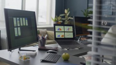 Gündüz vakti boş boş uzay ofisindeki ekranlarda iş grafikleri olan bilgisayar monitörleri ve dizüstü bilgisayarlardan el bilgisayarı çekilen kimse yok.