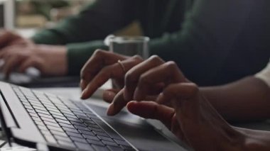 Tanımlanamayan meslektaşların laptoplarda oturup açık uzay ofisinde birlikte çalışmalarının yavaş çekimleri.
