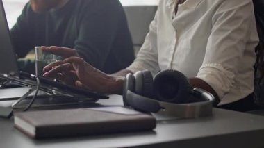 Dizüstü bilgisayarlarla çalışan genç meslektaşlarını yakın çekime al. Açık uzay ofisindeki ofis masasında pencere kenarına oturt.