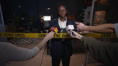 Genç Afro-Amerikan kadın polis memurunun orta ölçekli görüntüsü. Basının kendisiyle iş yerinde yaptığı sorgulama sorularını yanıtlıyor. Soruşturma detaylarını paylaşıyor.