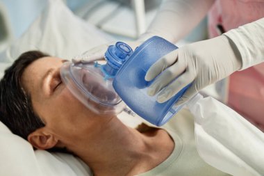 Hastanedeki hastaya oksijen desteği veren bir tıbbi uzman. Temel sağlık hizmetlerini sunan bakım ve tıbbi ekipmanlara odaklanın