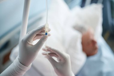 Eldivenli eller tıbbi enjeksiyonu hazırlıyor. Hastanenin arka planında dinleniyor. Görünürde tıbbi cihaz yok.