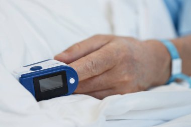 Tıbbi bakım için hastaneye kaldırılırken oksijen seviyelerini izlemek için parmaklarında nabız oksimetresi olan hastaların yakın çekim görüntüleri.