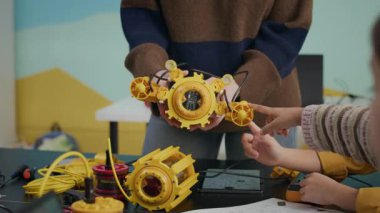 Tanımlanamayan bir öğretmenin robot modellerini modern iyi donanımlı sınıflarda masalarda oturan ve robot kulübüne giden meraklı çocuklara göstermesi.