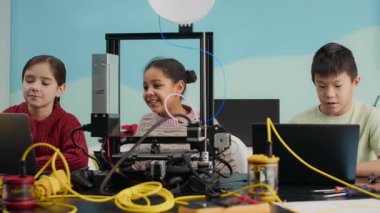 Okulda STEM dersinde laptopların önünde oturan meraklı çoklu etnik çocukların orta boy fotoğrafı.