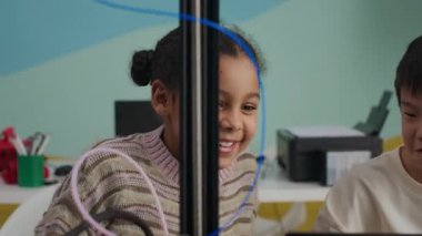 Laptop ve 3D yazıcının önünde oturan neşeli çoklu etnik çocukların modern iyi donanımlı sınıflarda STEM projesinde birlikte çalışmalarını çekiyoruz.