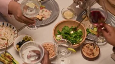 Aile toplantısı sırasında kırmızı şarap bardaklarını tokuşturup alkolsüz kokteyller içen tanınmayan insanların yüksek açılı çekimi.