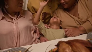 Kutlamada çocukların burnuna dokunan küçük çocukla oynayan mutlu siyahi bir ailenin orta boy yemek masasından orta boy fotoğraf, el kamerası.